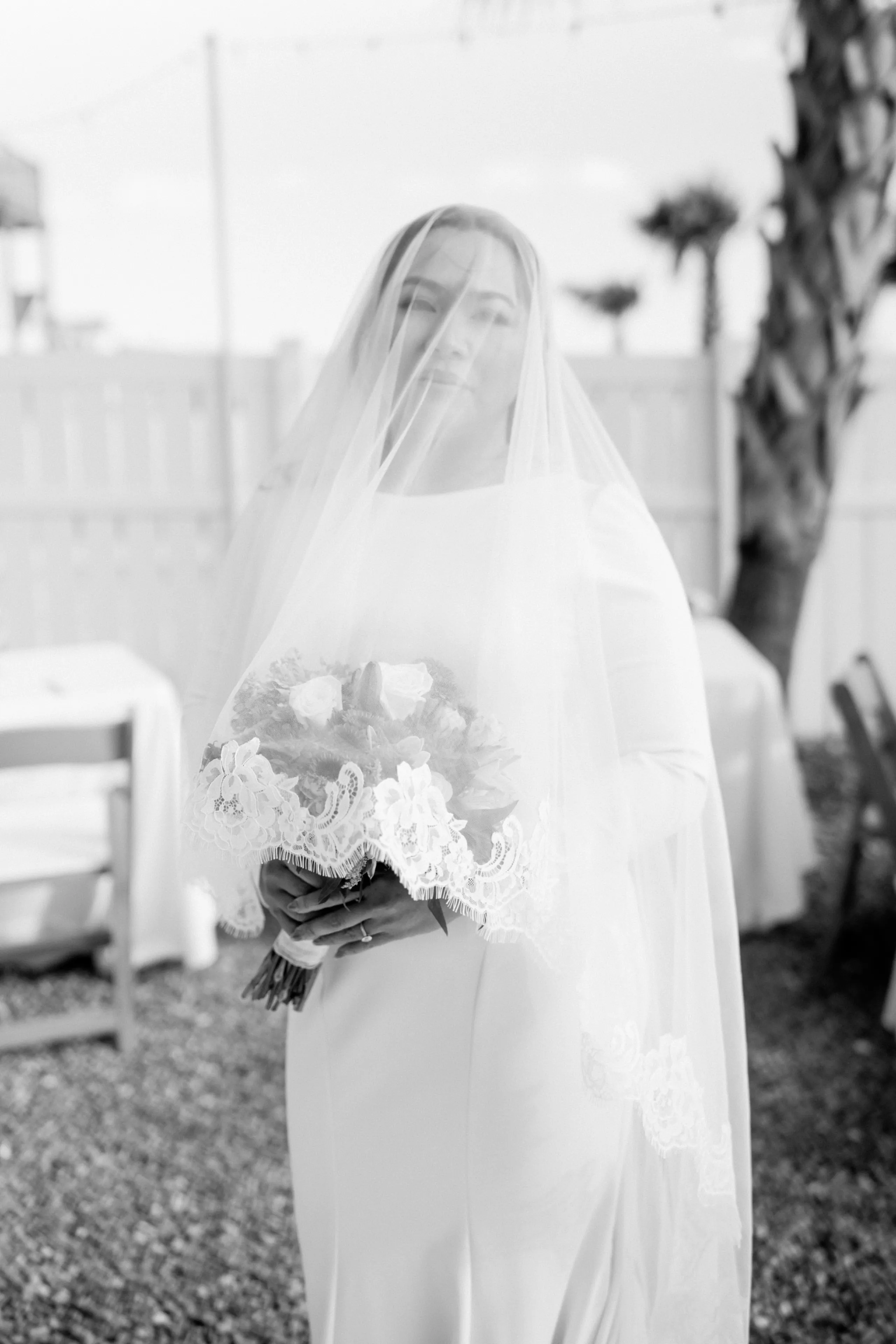 An intimate beach wedding ceremony with guests watching a couple exchange vows.