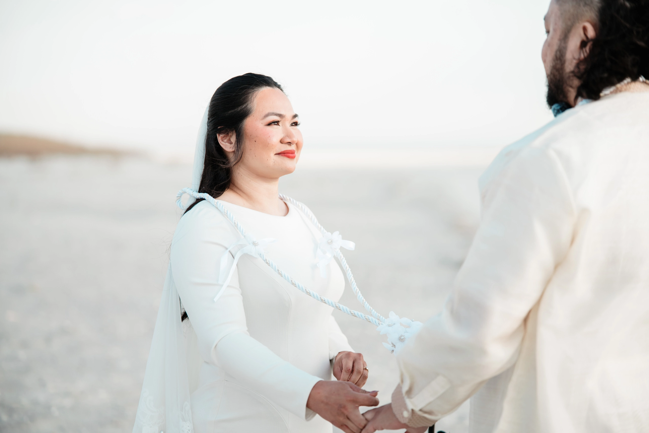 Winter photographer wearing puffy jacket and beanie takes photo with professional camera in woods.