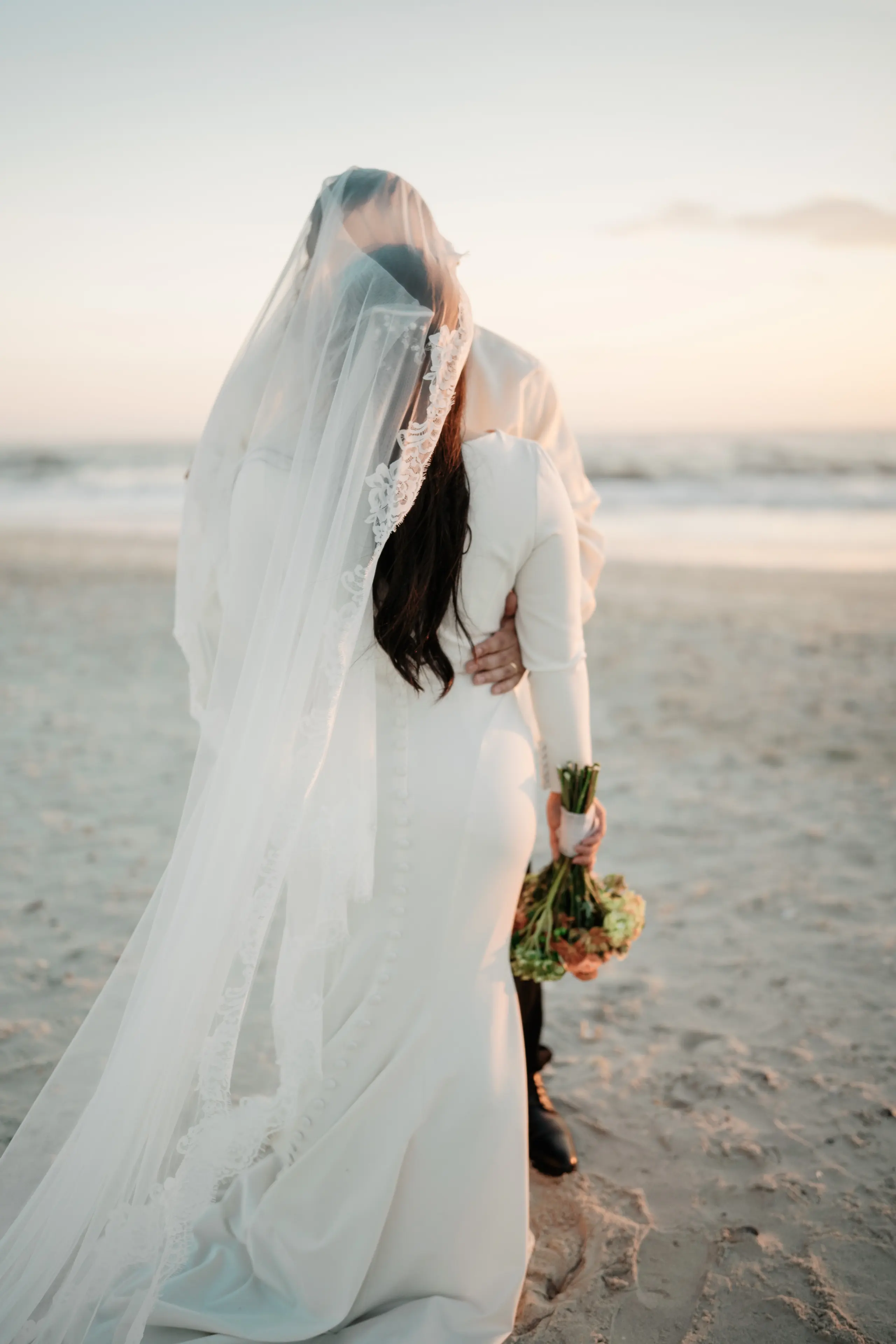 Intimate couple embracing on beach at golden hour.