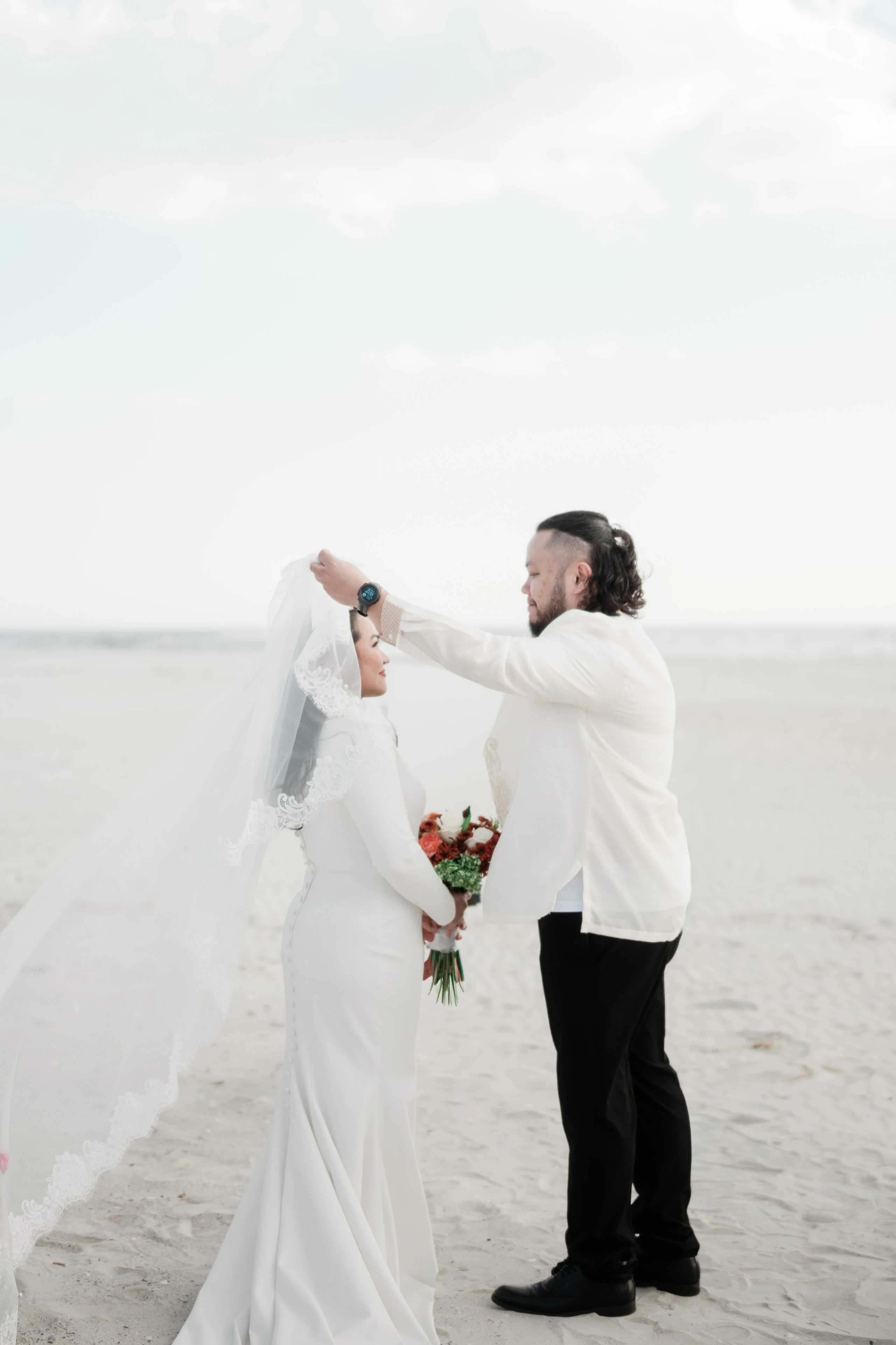 Professional photographer in formal attire and hat holding camera in garden setting.
