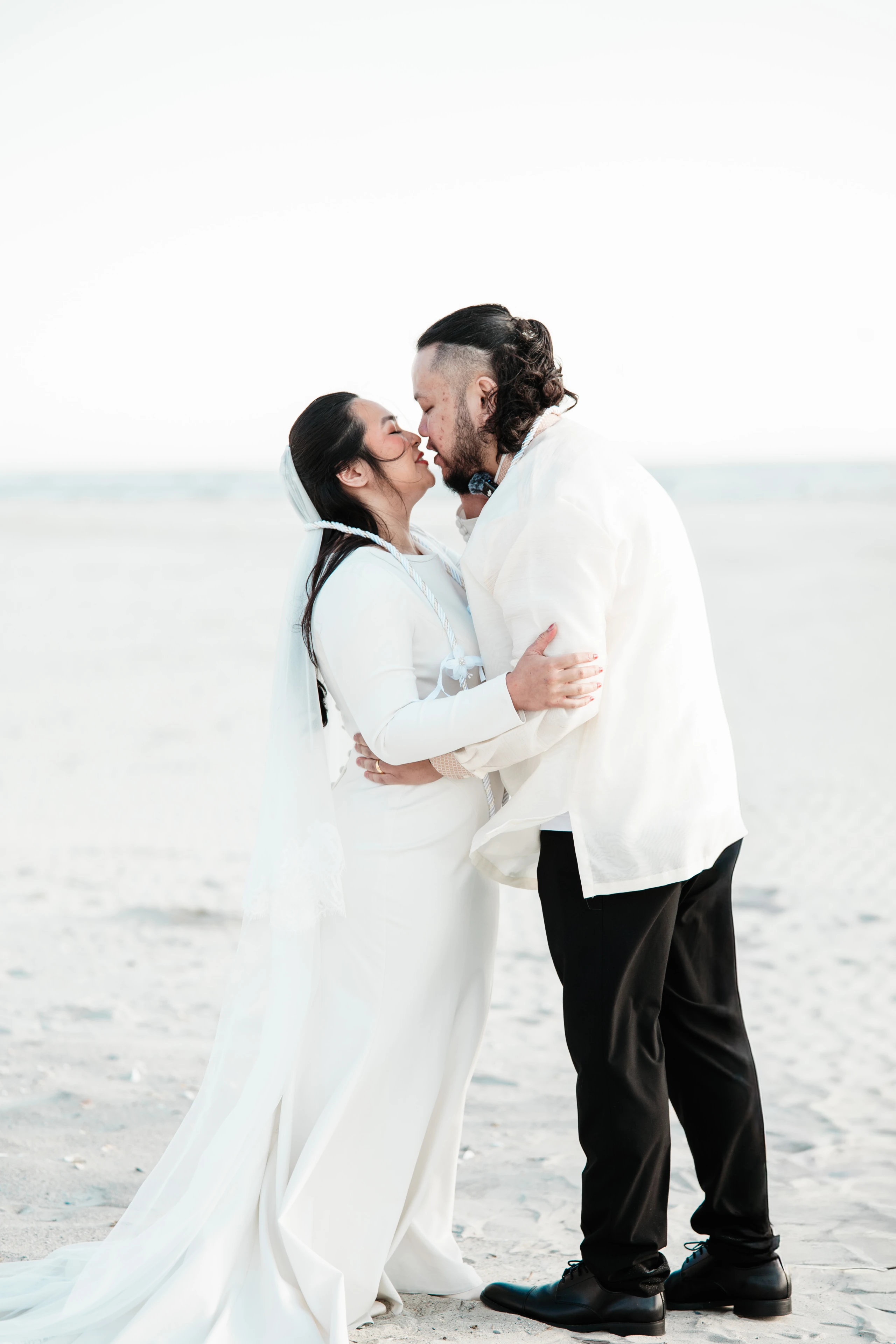 A happy family poses together with their fluffy goldendoodle dog on a sunny beach.