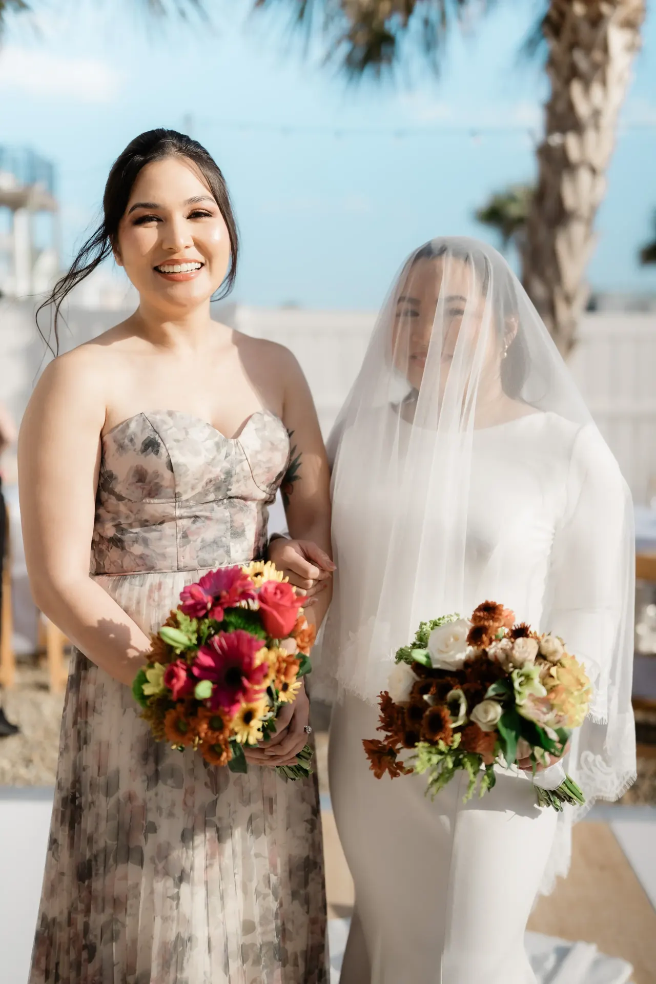 Newlywed couple standing together by reflecting pool surrounded by evergreen trees.