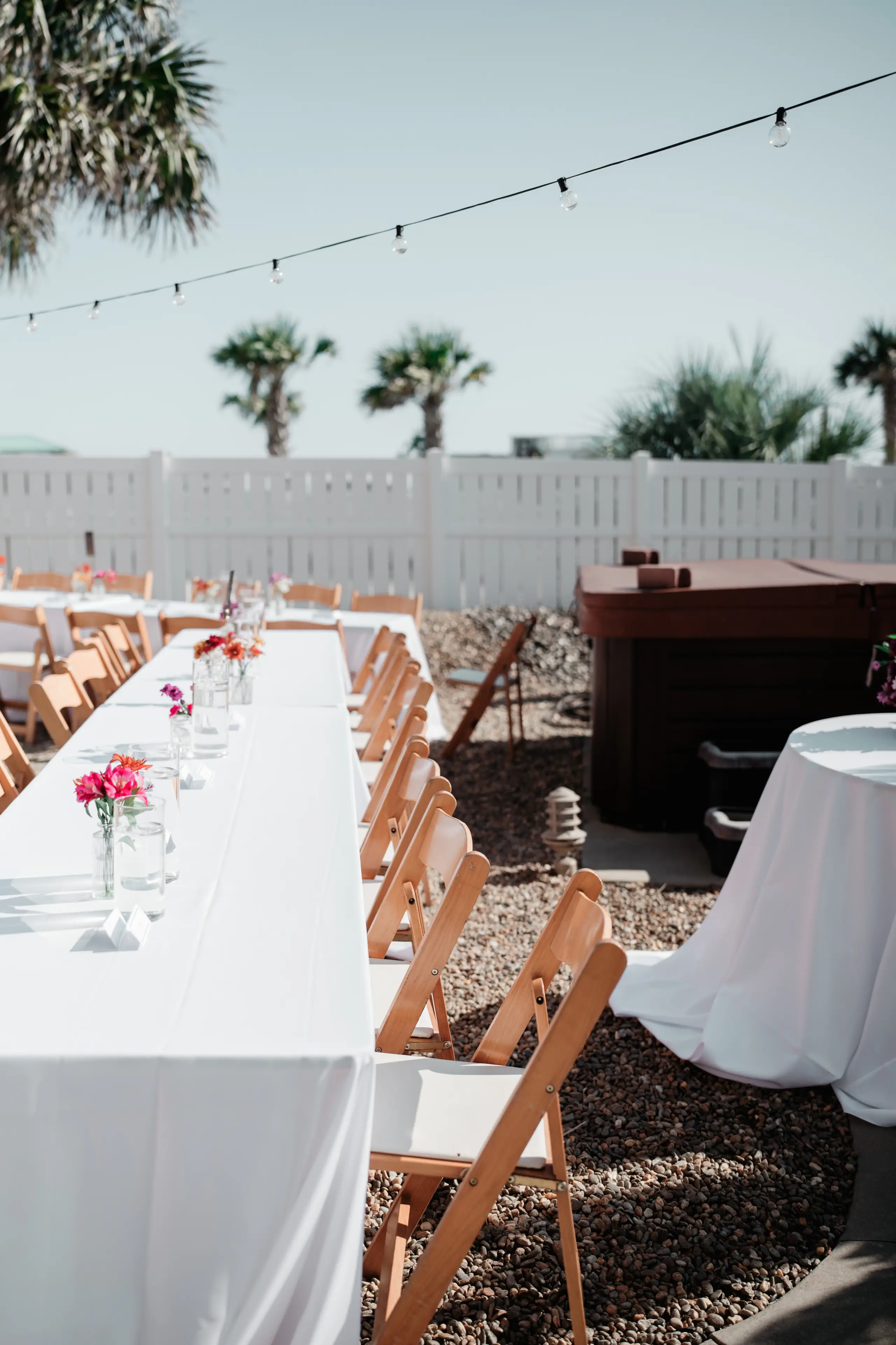 Bride in white gown holding bouquet poses on stone path with two men in dark suits.