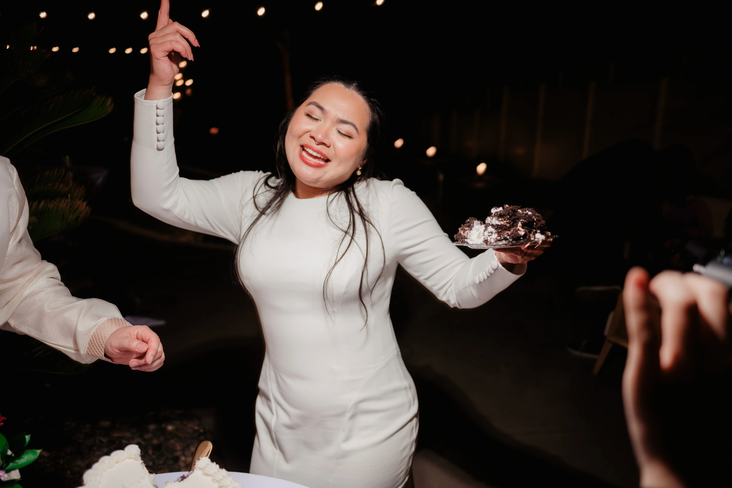 Wedding party poses in formal attire against garden backdrop.